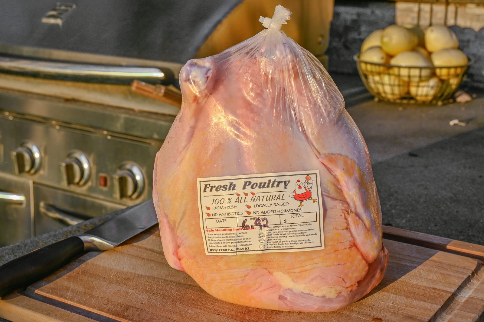 Whole chicken in clear packaging with a Fresh Poultry label reading 100 percent all natural, no antibiotics, no added hormones